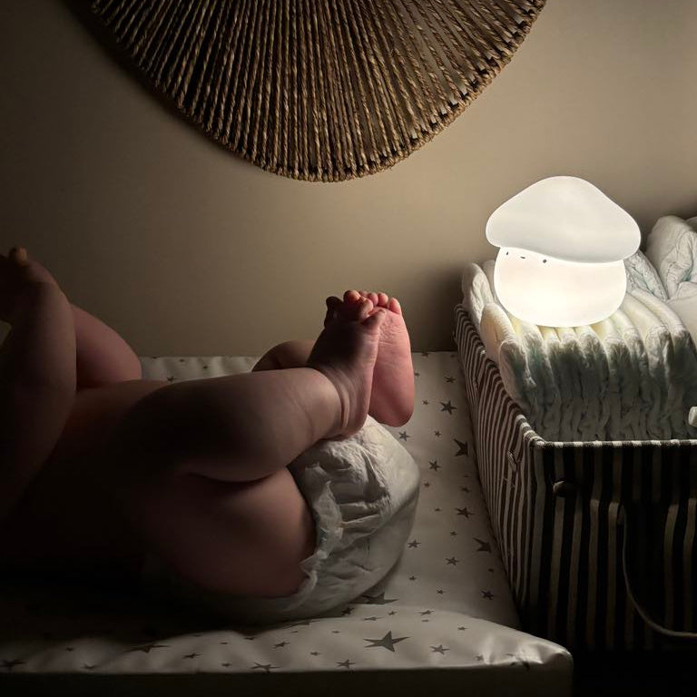 Baby getting a diaper change with a mushroom-shaped night light on a nightstand