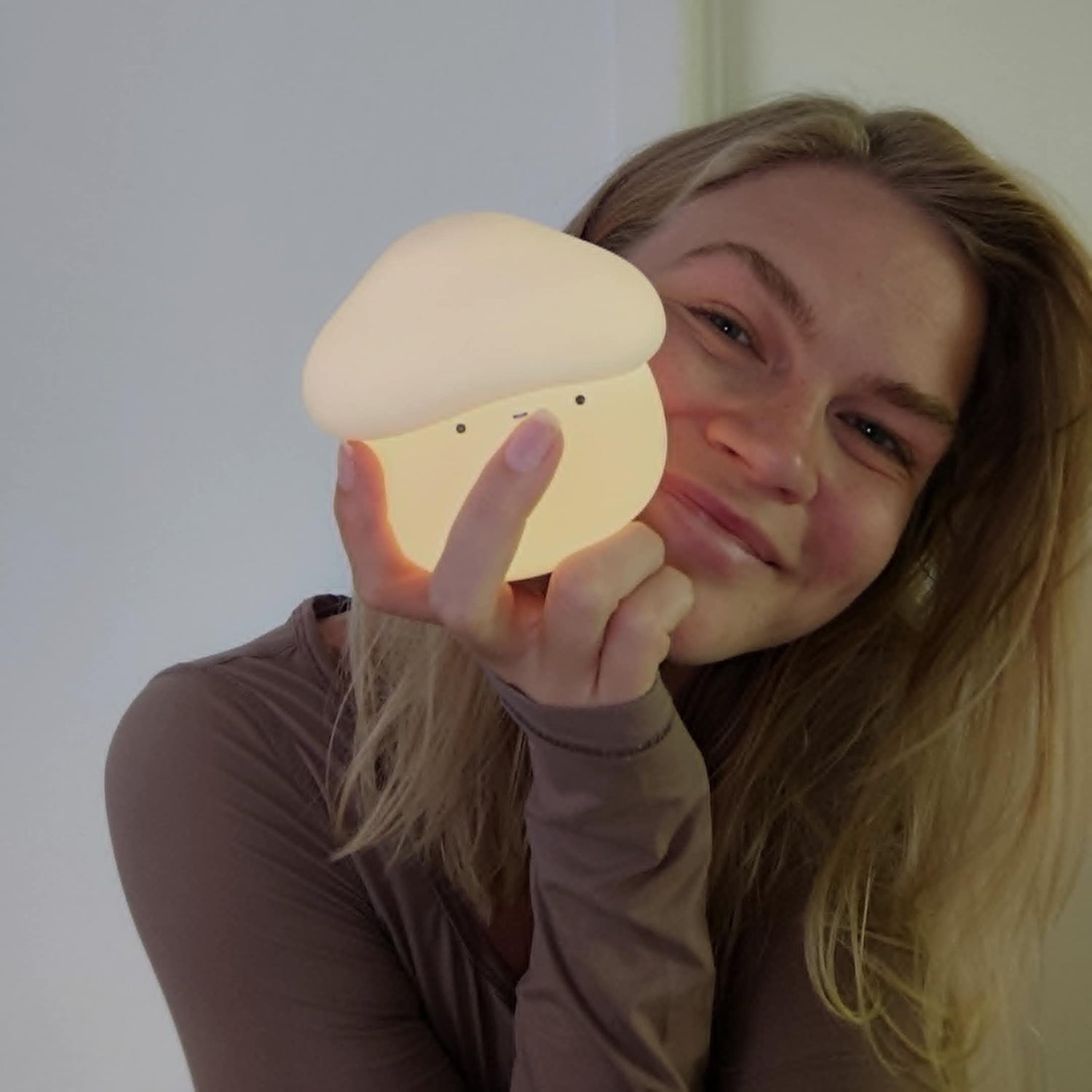 Person holding a glowing mushroom-shaped night light against a plain background